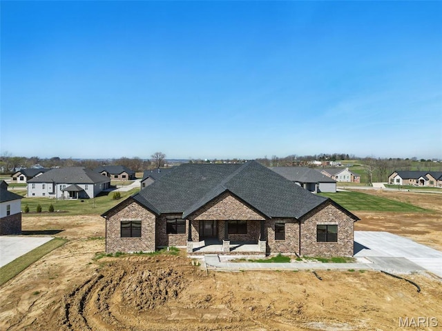 view of front of home featuring a residential view, brick siding, and roof with shingles