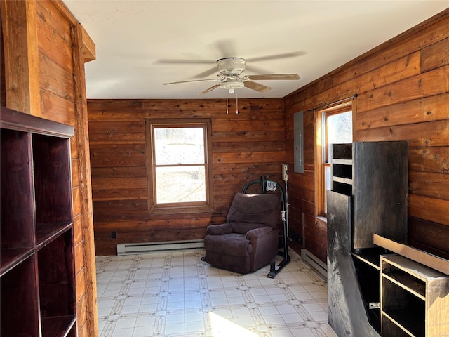 living area with a baseboard heating unit, light flooring, a ceiling fan, and wooden walls