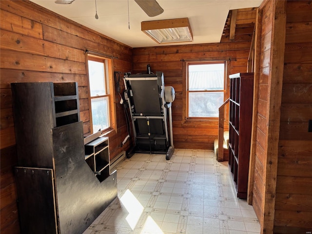 miscellaneous room featuring light floors, wood walls, a ceiling fan, and a baseboard heating unit