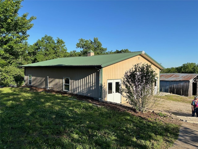 view of property exterior featuring a yard, metal roof, and a chimney