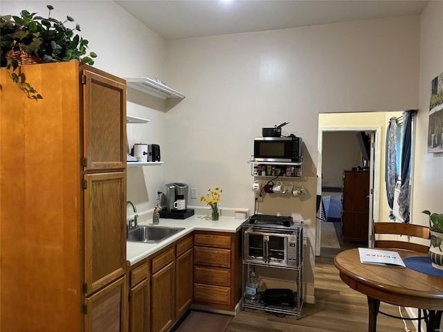 kitchen featuring a sink, dark wood-style flooring, brown cabinetry, and light countertops