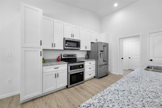 0 Hickory Lndg, De Soto, MO 63020 - kitchen with appliances with stainless steel finishes, baseboards, white cabinets, high vaulted ceiling, and light wood finished floors