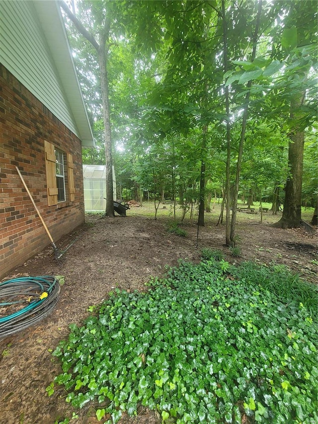 view of yard featuring a greenhouse and an outdoor structure