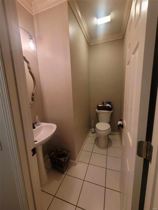 half bathroom with tile patterned floors, crown molding, toilet, and baseboards