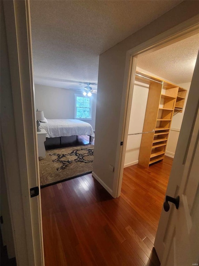 hall with a textured ceiling and dark wood-style flooring