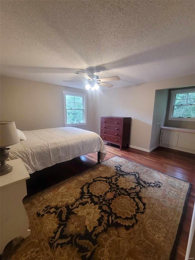 bedroom with a textured ceiling, wood finished floors, a ceiling fan, and baseboards