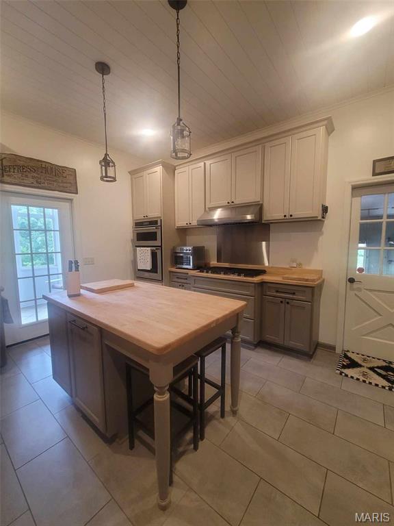 16225 Shady Ln, Dexter, MO 63841 - kitchen featuring under cabinet range hood, stovetop, hanging light fixtures, and light tile patterned floors