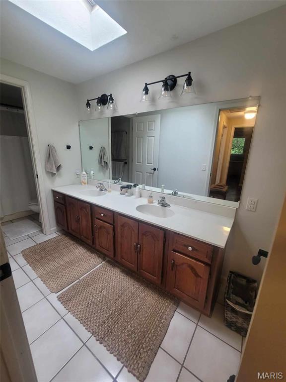 16225 Shady Ln, Dexter, MO 63841 - full bathroom with a skylight, tile patterned floors, double vanity, and toilet