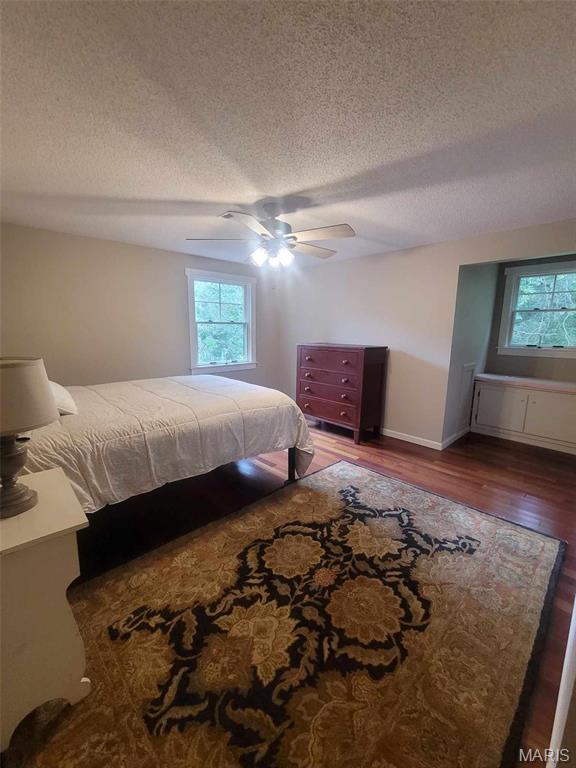 16225 Shady Ln, Dexter, MO 63841 - bedroom featuring a textured ceiling, multiple windows, wood finished floors, ceiling fan, and baseboards