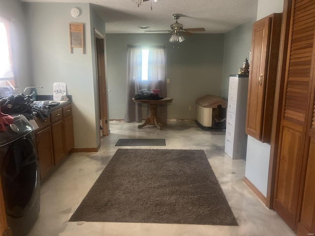 bathroom with a ceiling fan, washer and dryer, a textured ceiling, and baseboards