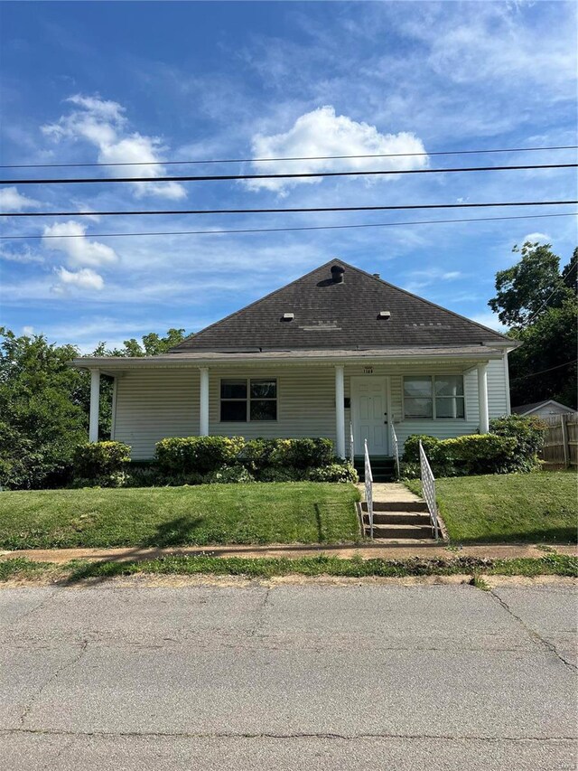 bungalow-style home featuring a front lawn and roof with shingles