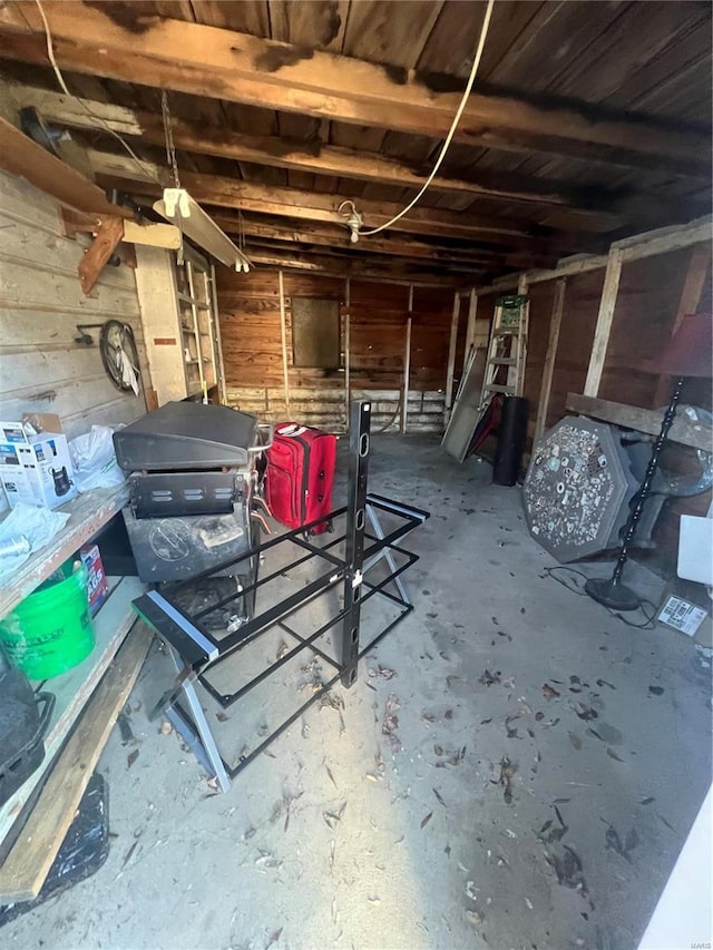 misc room featuring concrete flooring and wooden walls