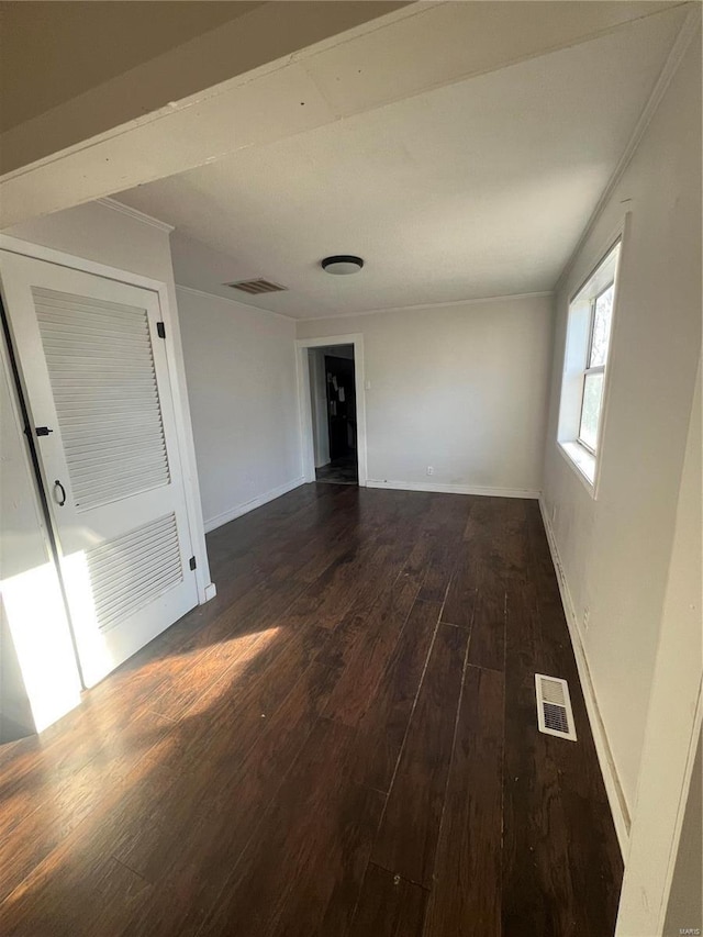 unfurnished room featuring dark wood-type flooring, baseboards, and ornamental molding