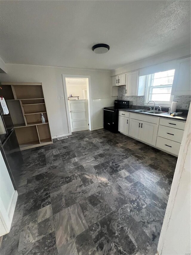 kitchen with white cabinets, a textured ceiling, black range with electric cooktop, dark countertops, and baseboards
