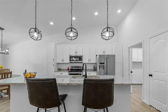 1523 Hickory Lndg, De Soto, MO 63020 - kitchen featuring stainless steel appliances, high vaulted ceiling, a kitchen breakfast bar, white cabinets, and a center island with sink