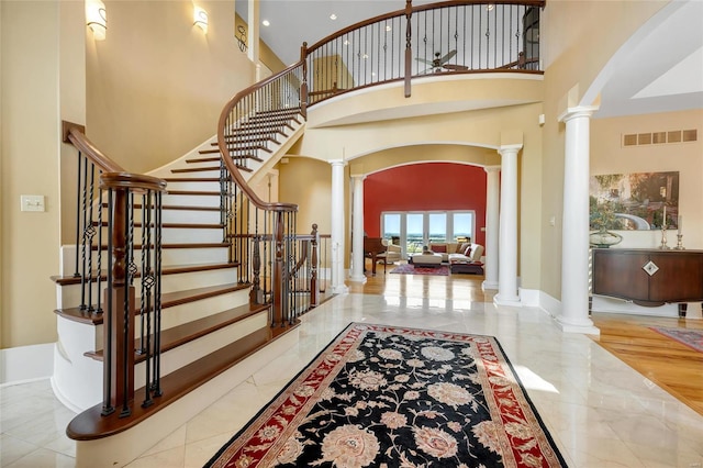 entryway featuring decorative columns, arched walkways, a towering ceiling, marble tiled floors, and stairway