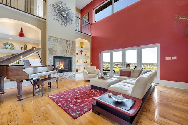 living area with a high ceiling, plenty of natural light, hardwood / wood-style floors, and a fireplace