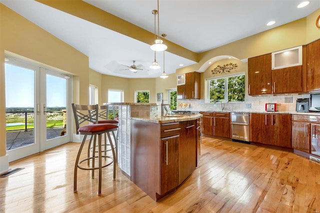 kitchen featuring french doors, a kitchen bar, light wood-type flooring, tasteful backsplash, and pendant lighting