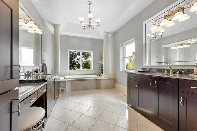 bathroom featuring decorative columns, a chandelier, tile patterned flooring, two vanities, and a garden tub