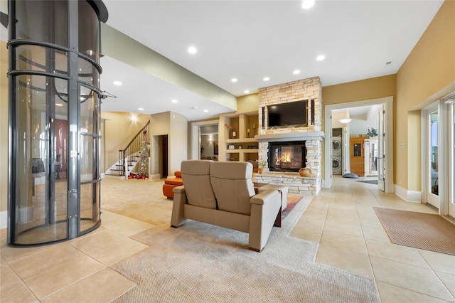 living room featuring light tile patterned flooring, a stone fireplace, recessed lighting, built in shelves, and stairs