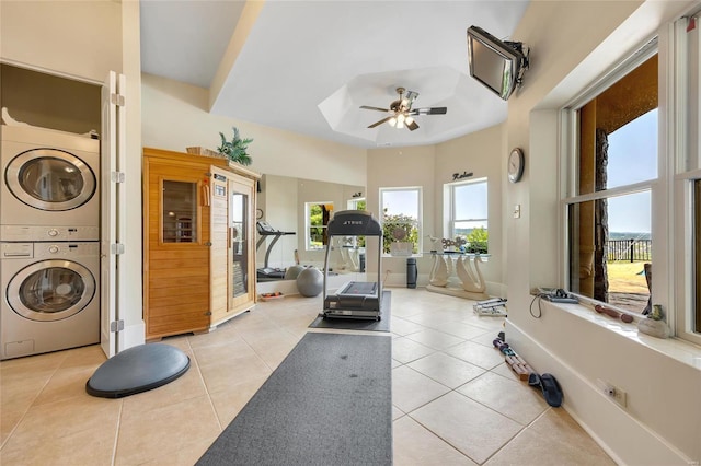 workout area with stacked washer / drying machine, a skylight, light tile patterned flooring, and a ceiling fan