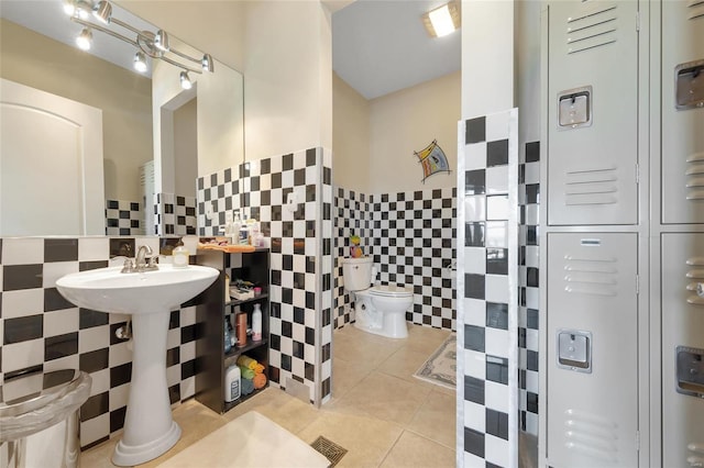 bathroom with tile walls, tile patterned flooring, toilet, and wainscoting