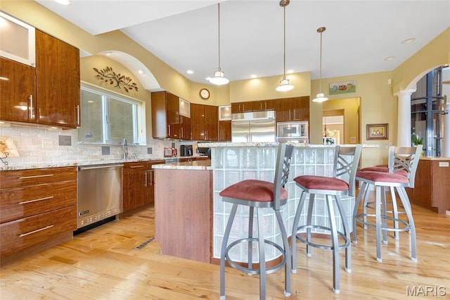 265 Deer Run Ln, Eureka, MO 63025 - kitchen featuring built in appliances, light wood-style flooring, tasteful backsplash, a kitchen breakfast bar, and arched walkways