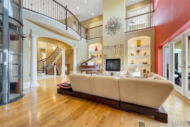 265 Deer Run Ln, Eureka, MO 63025 - living area with a high ceiling, ornate columns, a glass covered fireplace, built in features, and wood-type flooring