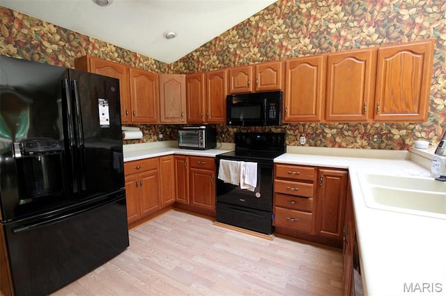 1710 Doe Run Dr, Vandalia, IL 62471 - kitchen with black appliances, wallpapered walls, light countertops, light wood-type flooring, and vaulted ceiling