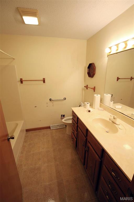 1710 Doe Run Dr, Vandalia, IL 62471 - bathroom with tile patterned flooring, vanity, a textured ceiling, and  shower combination