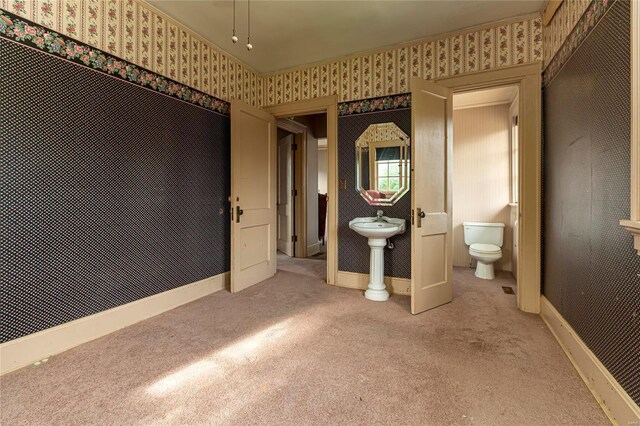 202 Poplar St, Harrisburg, IL 62946 - unfurnished bedroom featuring carpet flooring, wallpapered walls, baseboards, ensuite bath, and a sink