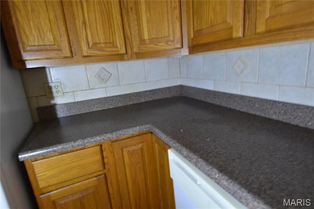 7617 Ivory Ave, Saint Louis, MO 63111 - kitchen featuring tasteful backsplash, dark countertops, brown cabinetry, and dishwasher