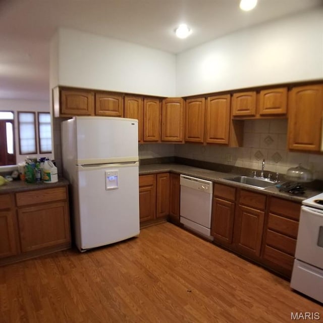 7617 Ivory Ave, Saint Louis, MO 63111 - kitchen featuring white appliances, a sink, brown cabinets, dark countertops, and light wood-style floors