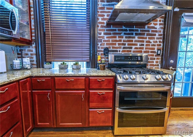 3630 Flad Ave, Saint Louis, MO 63110 - kitchen with stainless steel appliances, extractor fan, dark brown cabinets, and light stone counters