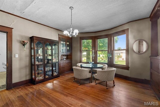 302 E Walsh St, Montgomery City, MO 63361 - dining space featuring wood-type flooring, a chandelier, ornamental molding, a textured ceiling, and baseboards