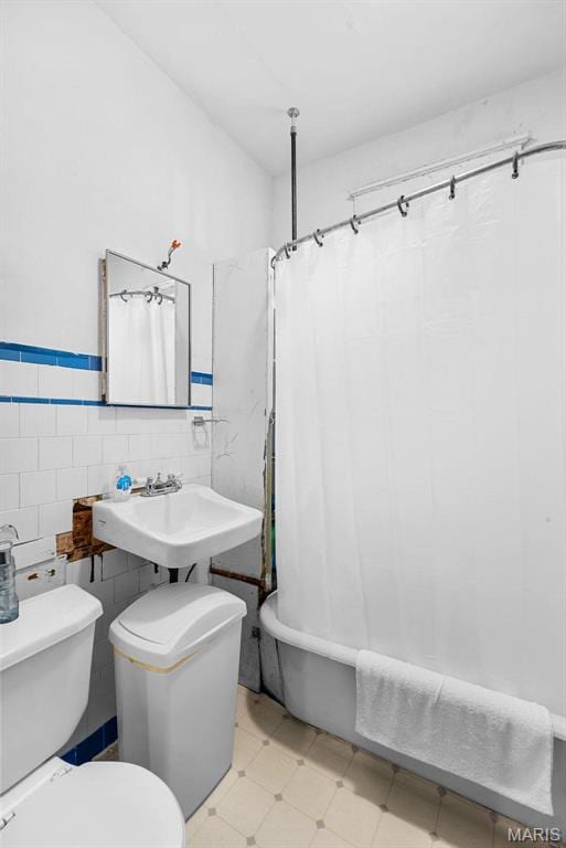 302 E Walsh St, Montgomery City, MO 63361 - bathroom featuring toilet, tile patterned floors, a sink, shower / bath combination with curtain, and tile walls
