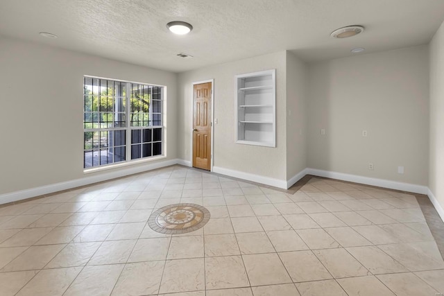 547 County Road 448, Poplar Bluff, MO 63901 - empty room featuring built in shelves, a textured ceiling, baseboards, and light tile patterned floors