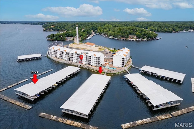 drone / aerial view of a nearby body of water and a heavily wooded area