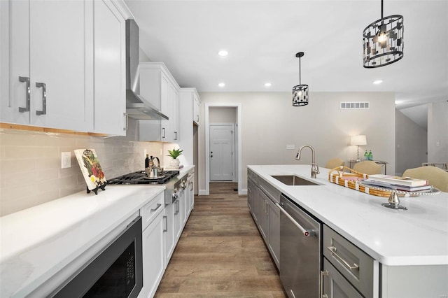 8817 Moritz Ave, Saint Louis, MO 63144 - kitchen with a sink, stainless steel appliances, wall chimney exhaust hood, wood finished floors, and backsplash