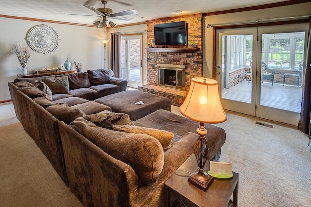 carpeted living area featuring crown molding, healthy amount of natural light, a brick fireplace, and ceiling fan