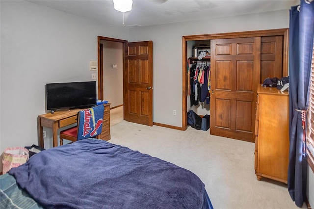 bedroom featuring light colored carpet, a closet, baseboards, and a ceiling fan