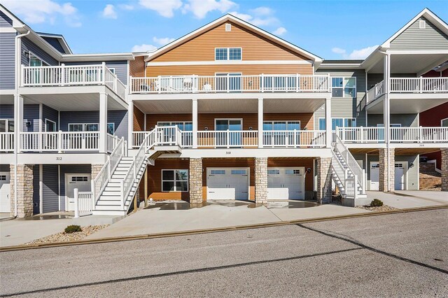 view of property with stairway, a garage, and driveway