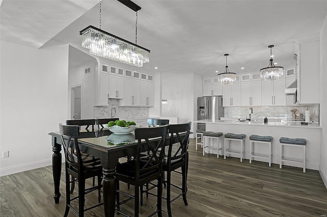 dining space with a chandelier, dark wood-type flooring, and baseboards