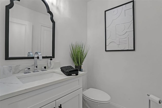 half bathroom with toilet, vanity, and baseboards
