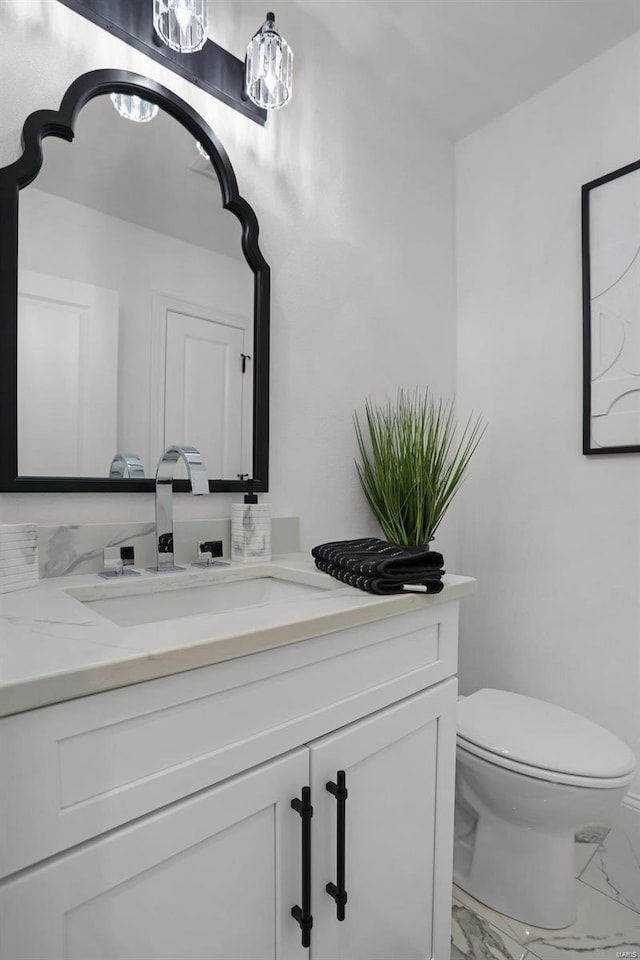 bathroom with marble finish flooring, vanity, and toilet