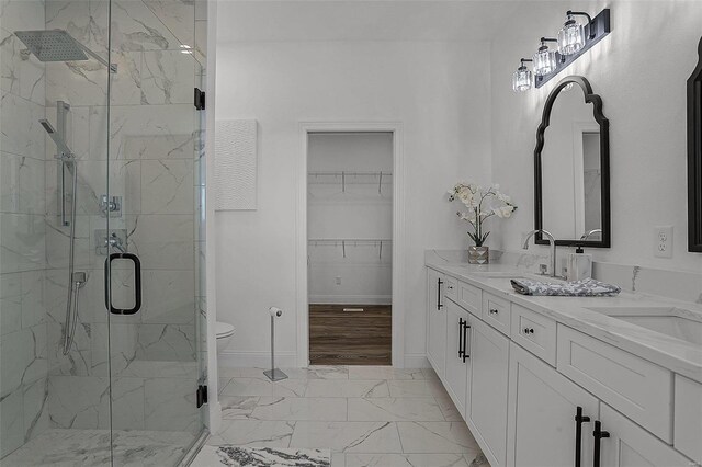 bathroom featuring a marble finish shower, marble finish flooring, baseboards, double vanity, and a spacious closet