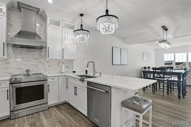 310 Captains Ct, Grafton, IL 62037 - kitchen featuring stainless steel appliances, a sink, wall chimney exhaust hood, a chandelier, and a peninsula