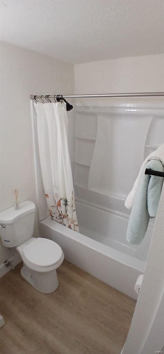 full bathroom with wood finished floors, toilet, and shower / tub combo