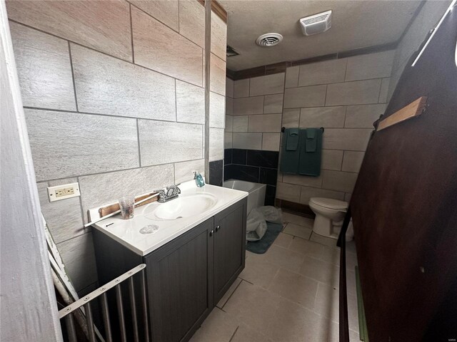 156 S Main St, Ironton, MO 63650 - bathroom with tile walls, toilet, vanity, a bathtub, and tile patterned flooring