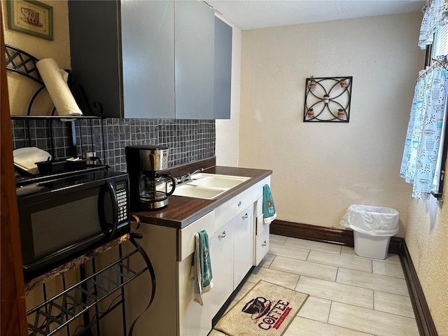 156 S Main St, Ironton, MO 63650 - kitchen featuring black microwave, dark countertops, a sink, baseboards, and backsplash